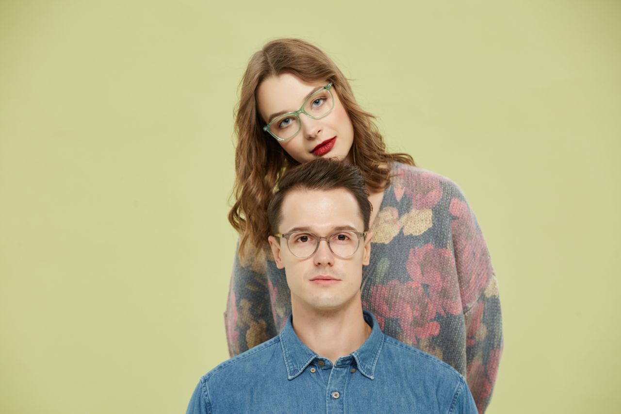 About A fashionable couple sporting trendy eyeglasses poses against a light background.